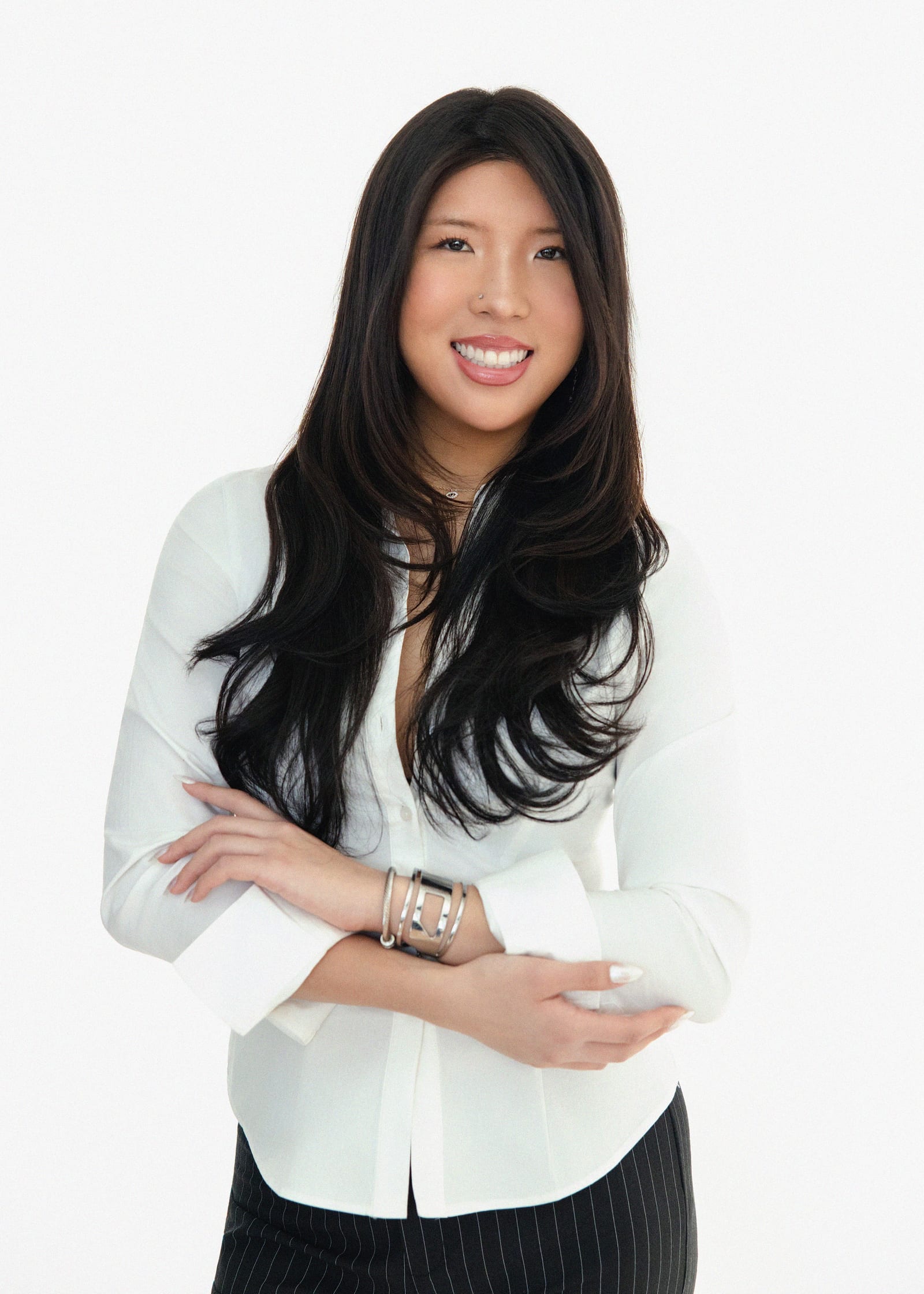 Professional in a white blouse with arms crossed against white