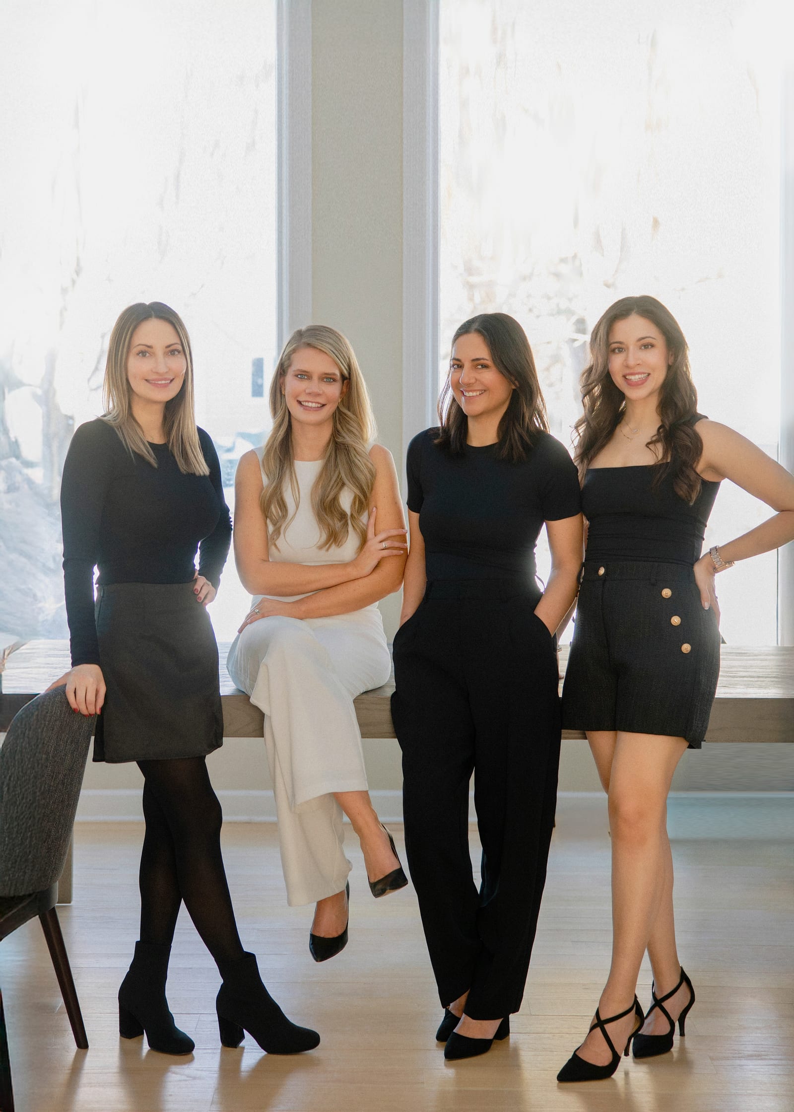 A team of four standing together in a bright white room