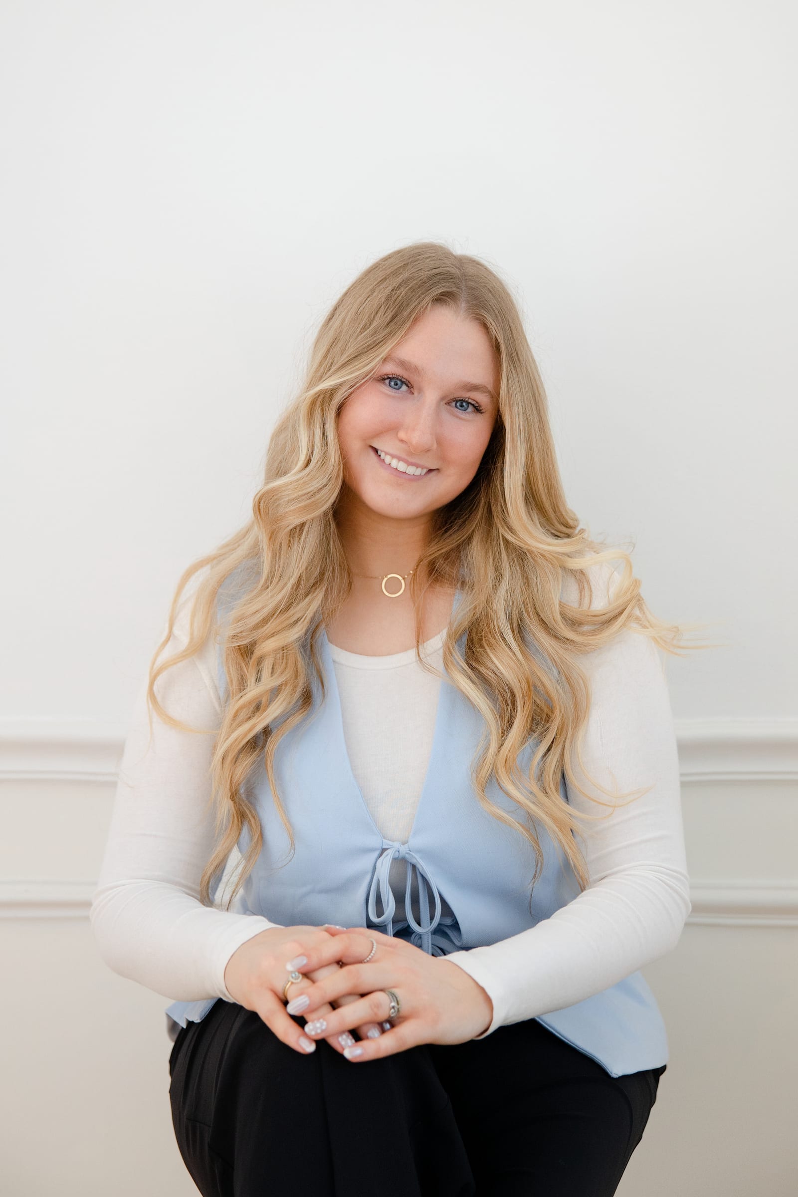 Professional in a pale blue top with hands clasped against white